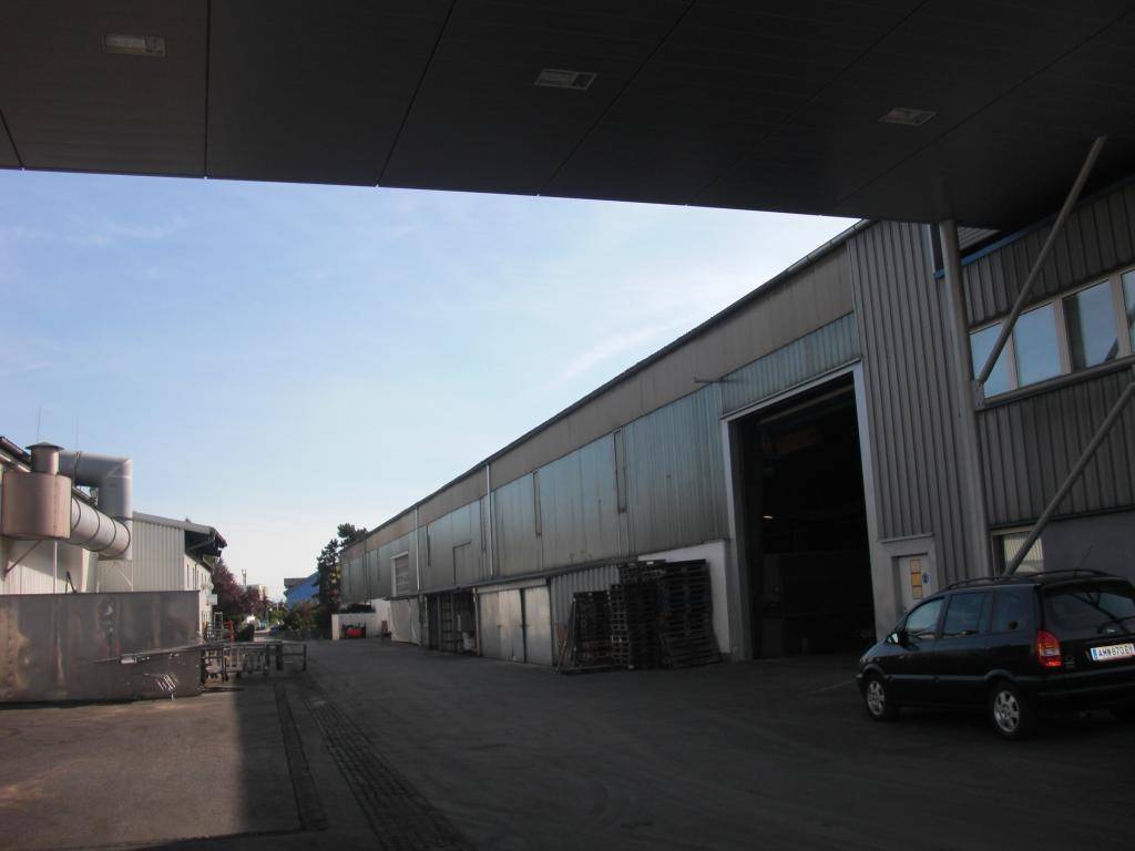 Industrielle Gebäudeansicht mit großen Rolltoren und einem gepflasterten Zufahrtsweg unter einem Vordach.