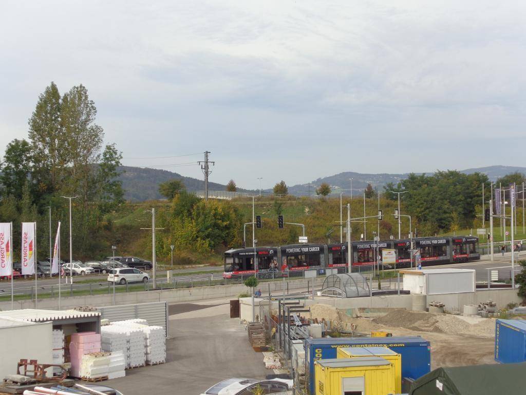 Blick auf eine Straße mit Bussen, umgeben von Hügeln und einem Bereich mit Baumaterialien.
