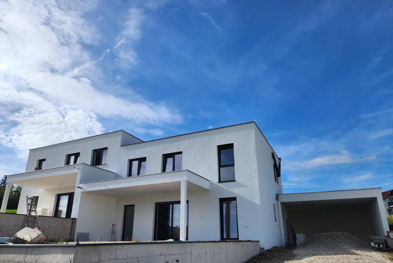 Neubau-Doppelhaushälfte in moderner Architektur mit Flachdach und integriertem Carport.
