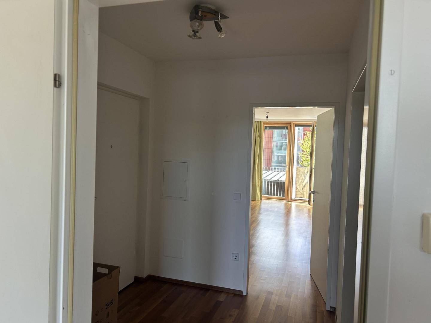 Heller Flur mit Holzboden, der zu einem weiteren Zimmer führt.
