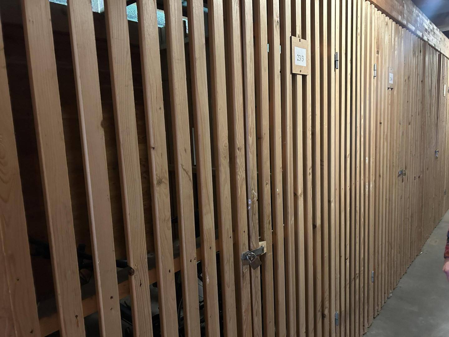 Abstellräume aus Holzlatten in einem Keller- oder Gemeinschaftsbereich.