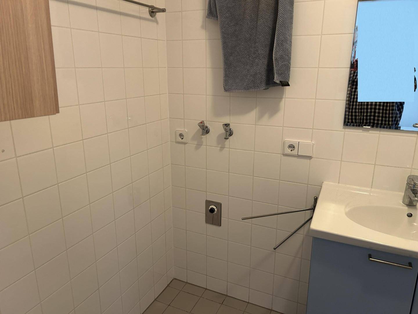 Badezimmer mit Waschbecken, Spiegel und weißen Wandfliesen.