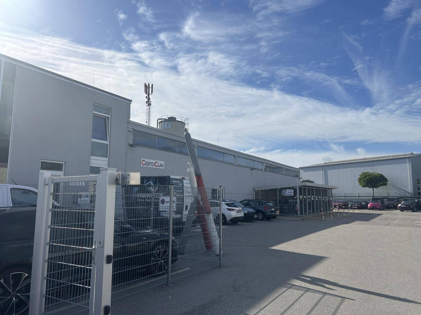 Außenansicht eines Gewerbegebäudes mit großem Parkplatz und einem markanten Propeller-Kunstwerk.