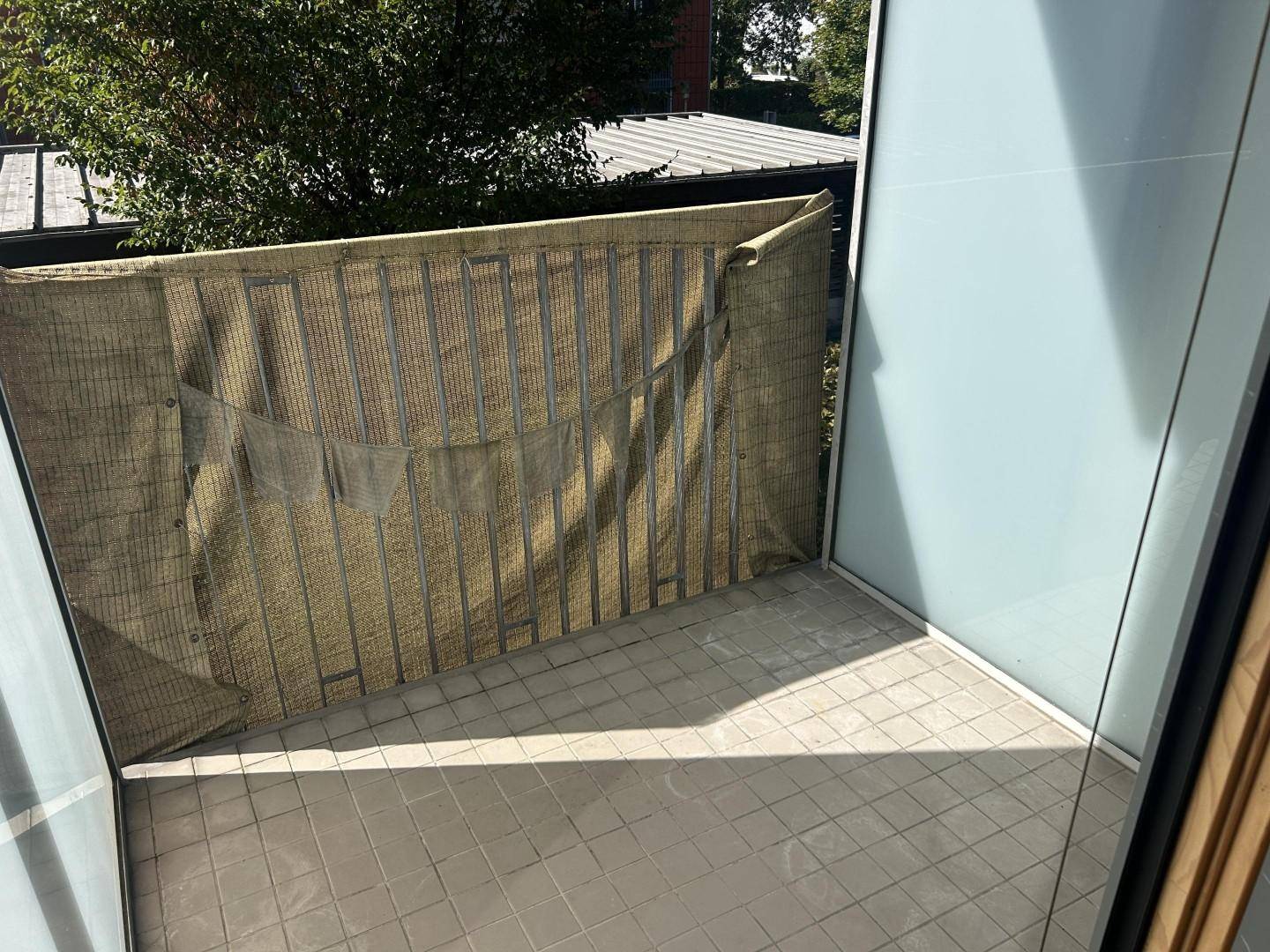 Balkon mit Fliesenboden und Sichtschutz für Privatsphäre.