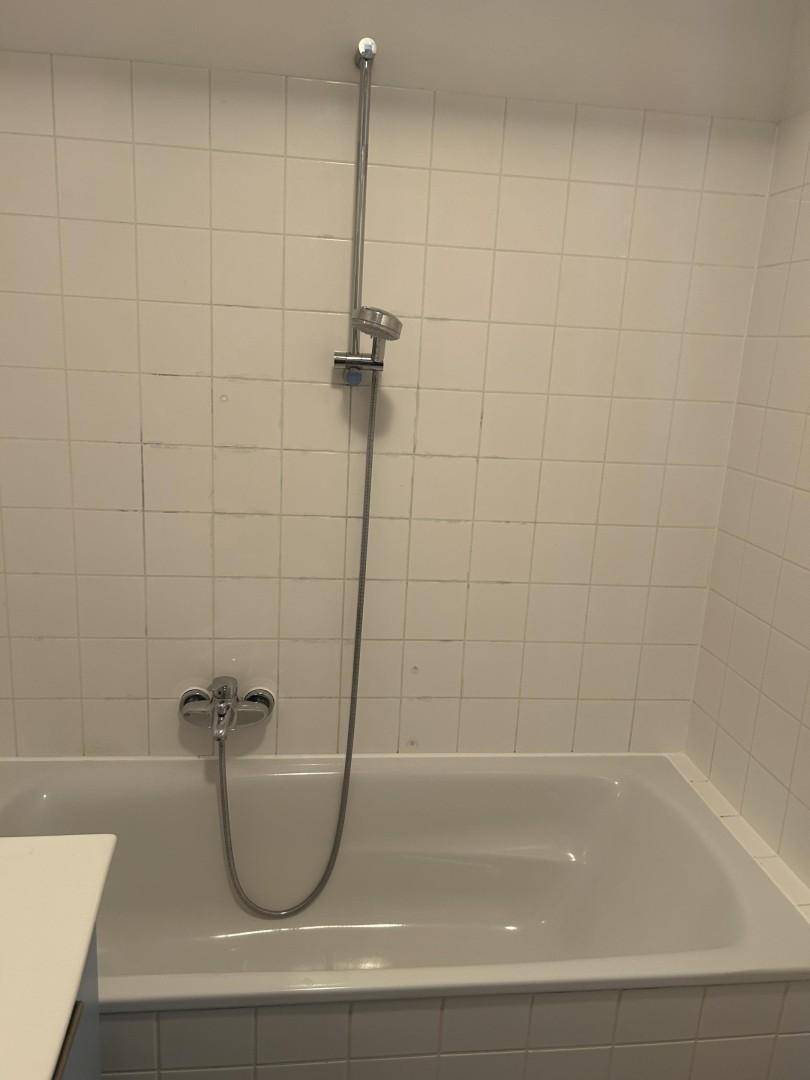 Badezimmer mit Badewanne und weißen Wandfliesen.