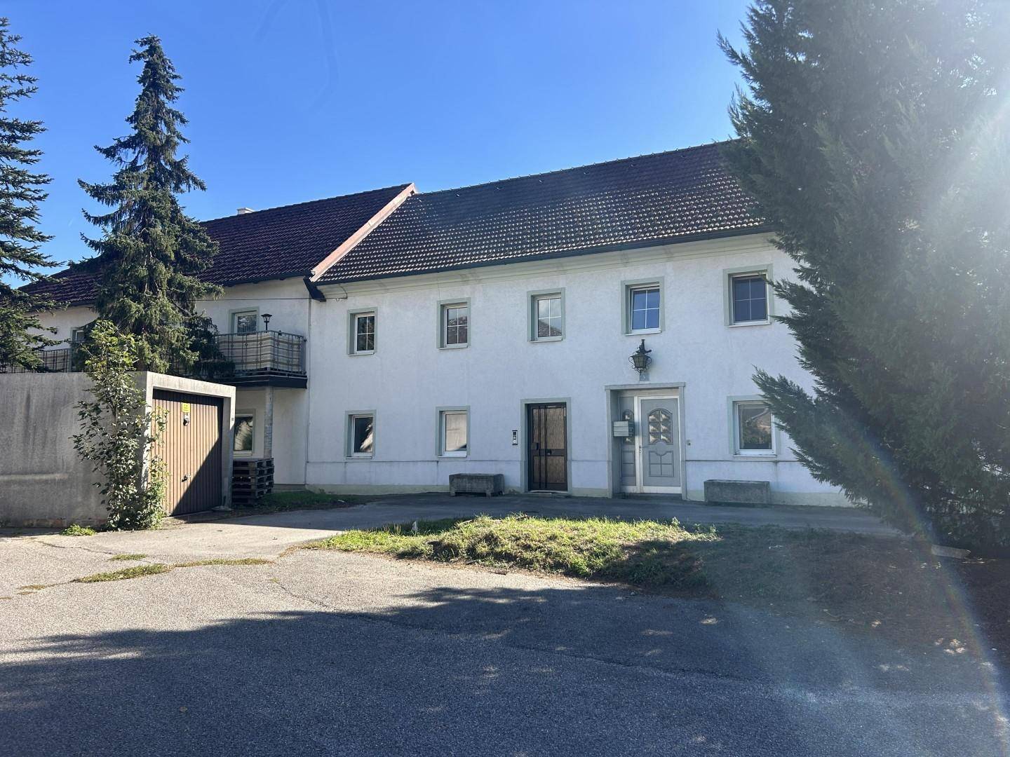 Hauptfassade des weißen Gebäudes mit rotem Dach und einer Garage auf der linken Seite.