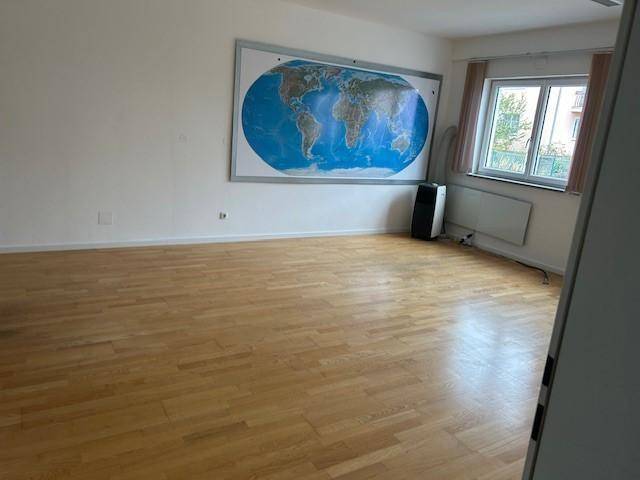 Heller Büroraum mit Holzboden, einer großen Weltkarte und einem Fenster, das Tageslicht hereinlässt.
