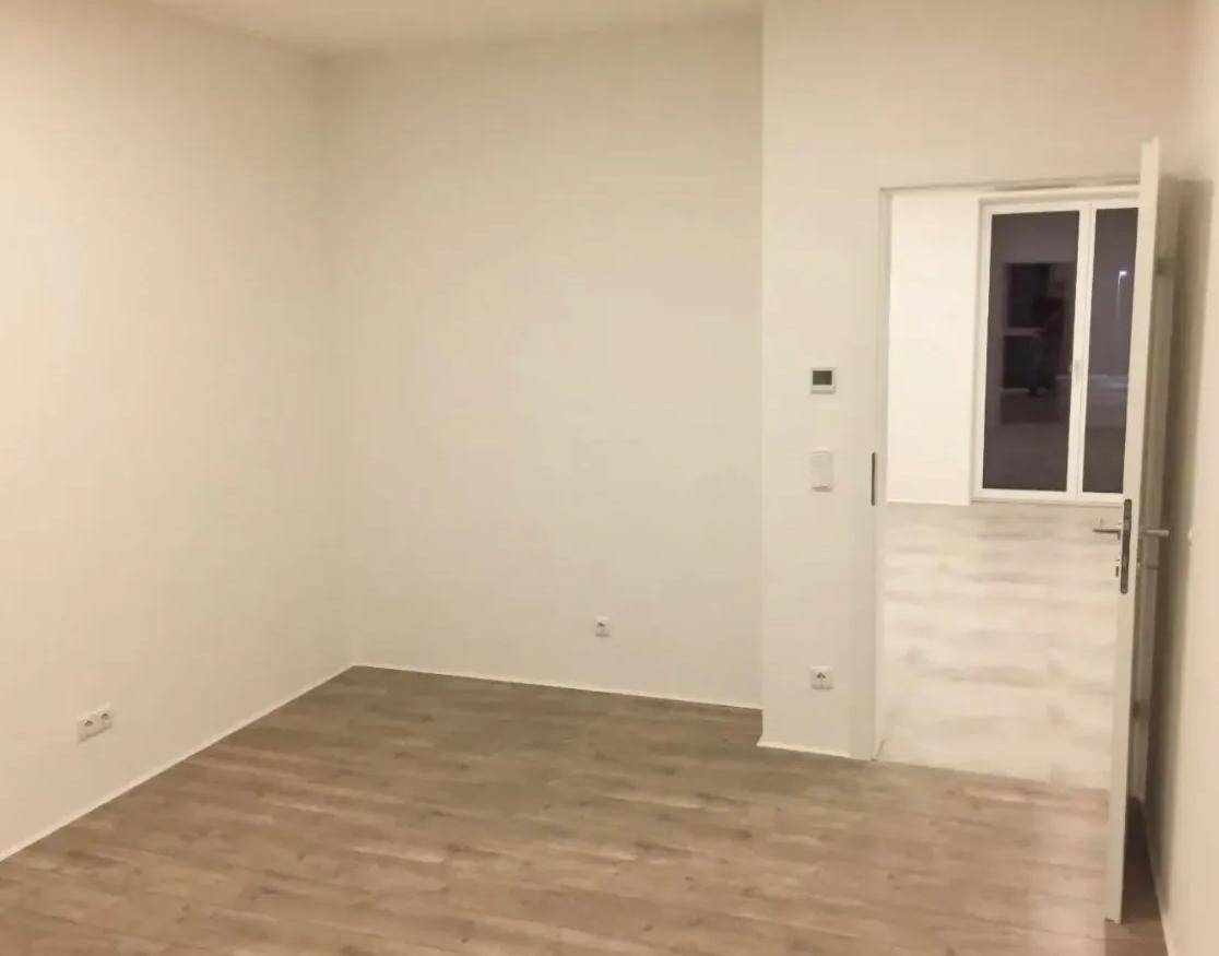 Leerer Raum mit hellem Laminatboden und weißen Wänden, bereit zur individuellen Gestaltung.