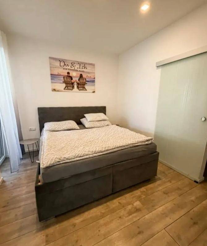 Gemütliches Schlafzimmer mit Doppelbett, hellem Holzboden und moderner Schiebetür.