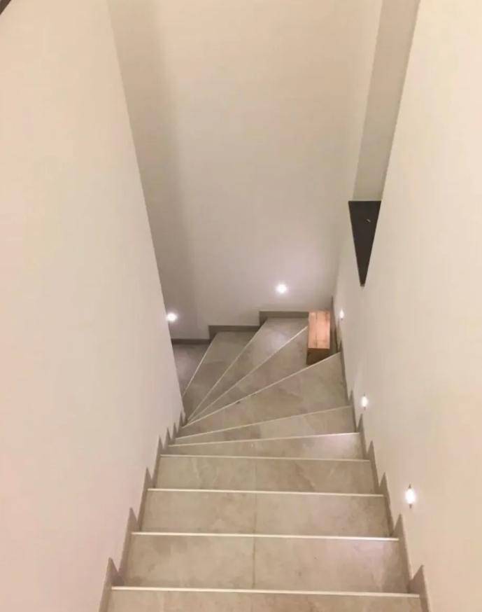 Moderne Treppe mit gefliesten Stufen und indirekter Beleuchtung für sicheren Aufstieg.