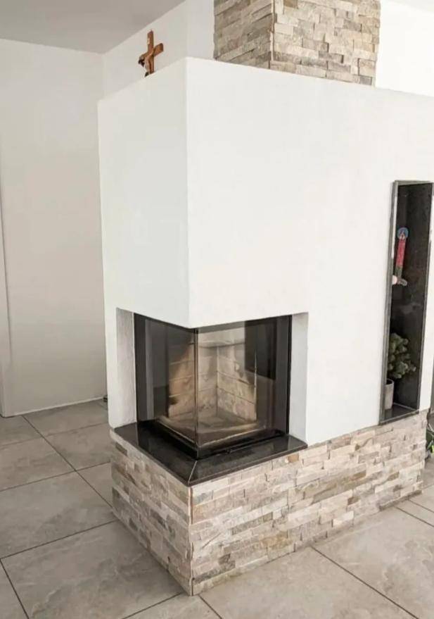 Moderner Kamin mit Glasfront und dekorativer Steinverkleidung, ein Blickfang im Wohnbereich.