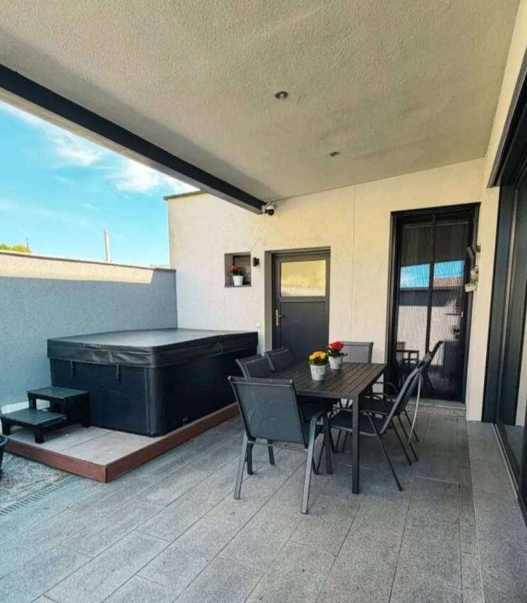 Überdachte Terrasse mit Whirlpool und gemütlicher Sitzgelegenheit für entspannte Stunden.
