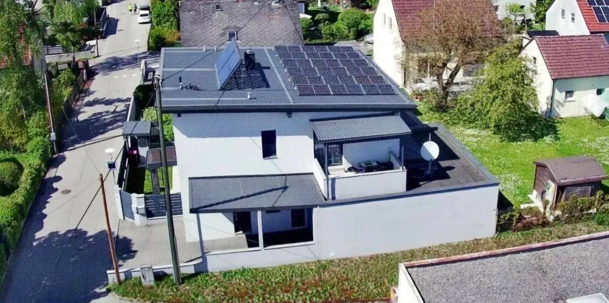 Luftaufnahme eines modernen Hauses mit Solaranlage auf dem Dach und Blick auf die Umgebung.