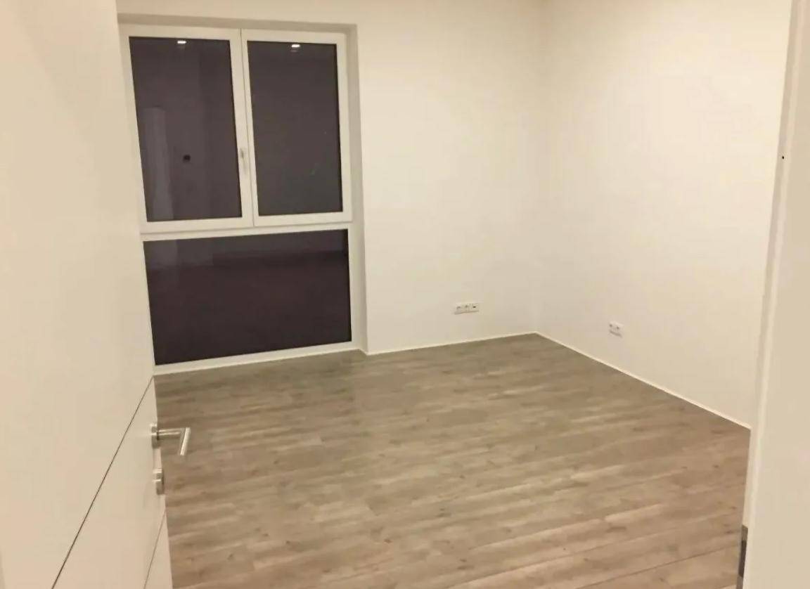 Unmöblierter Raum mit hellem Laminatboden und großem Fenster, ideal für ein Schlafzimmer.