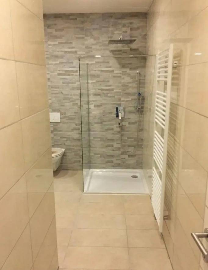 Modernes Badezimmer mit ebenerdiger Dusche, WC und beheiztem Handtuchhalter.