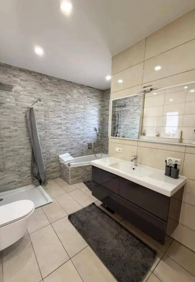Modernes Badezimmer mit Dusche, Badewanne, WC und einem einzelnen Waschbecken.