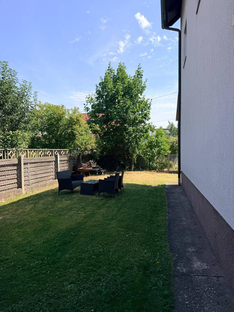 Gepflegter Gartenbereich mit Rasenfläche und einer kleinen möblierten Sitzecke im Freien.