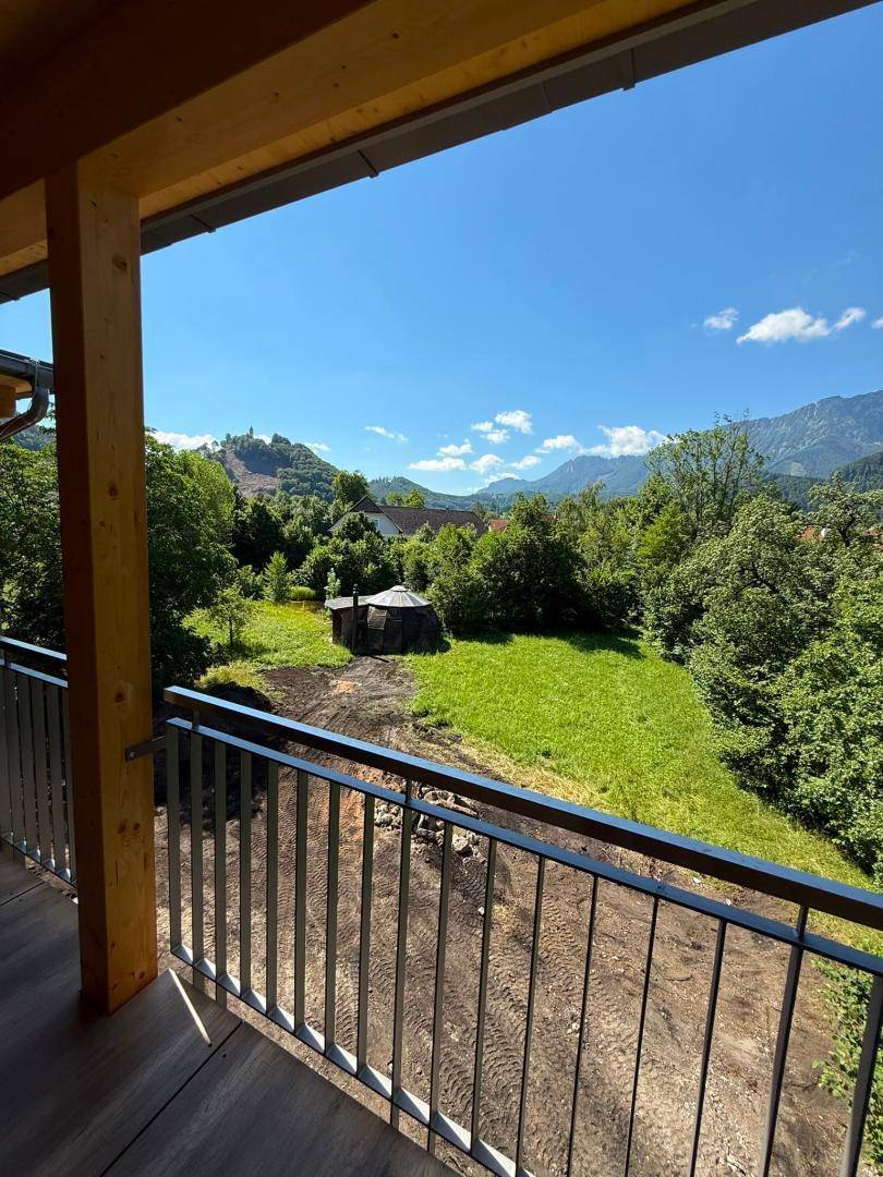 Geräumiger Balkon mit Holzboden und weitem Blick auf grüne Hügel und Berge.