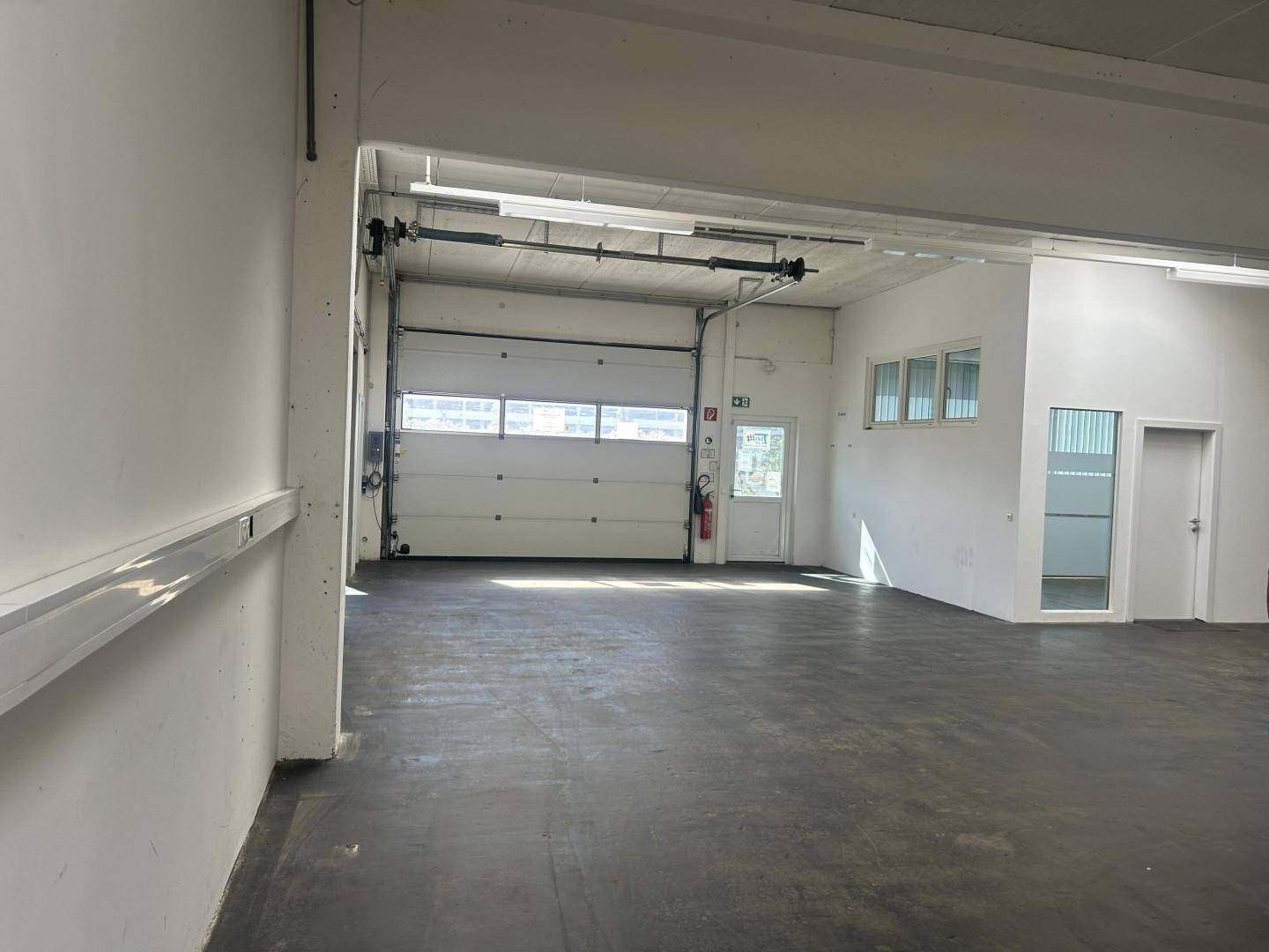 Große Lagerhalle mit Rolltor, Betonboden und viel Platz, geeignet für gewerbliche Nutzung oder als Garage.