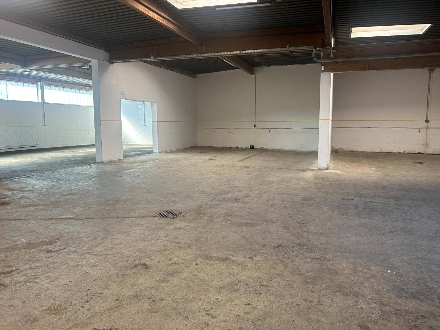 Weitläufige Lagerhalle mit hohen Decken, sichtbaren Holzbalken und Oberlichtern, ideal für industrielle Zwecke.