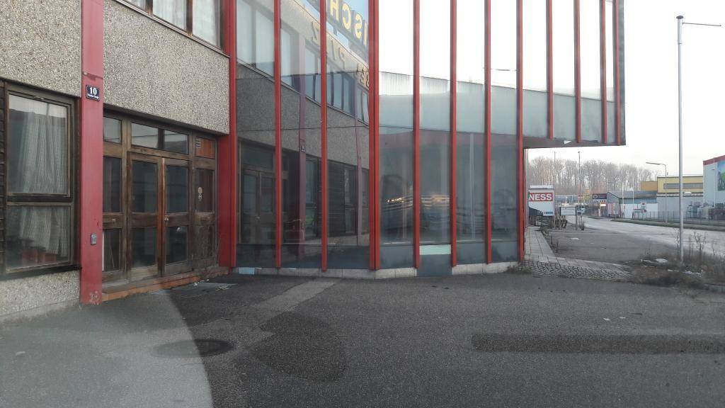 Gebäudefassade mit großen Glasflächen und roten vertikalen Elementen, die eine moderne Architektur betonen.