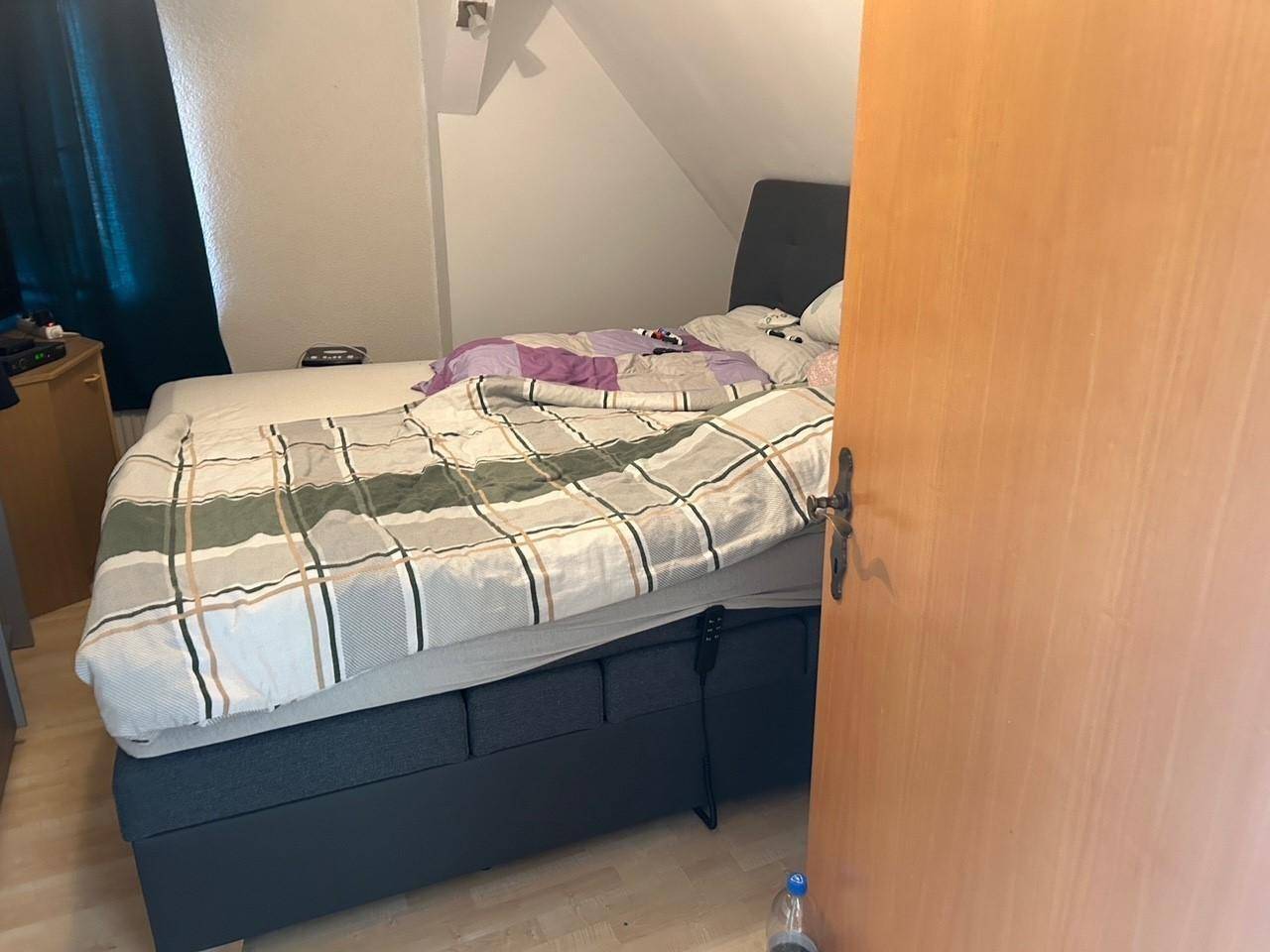 Schlafzimmer im Dachgeschoss mit Boxspringbett und schräger Decke.