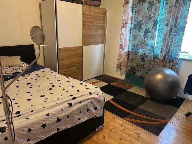 Schlafzimmer mit Doppelbett, großem Kleiderschrank und farbenfrohen Vorhängen.