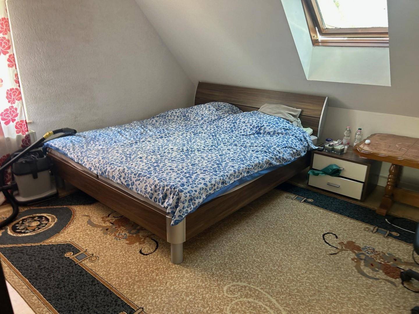 Gemütliches Schlafzimmer im Dachgeschoss mit Doppelbett, Teppichboden und Dachfenster.
