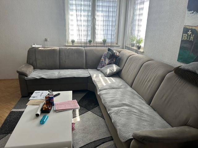Gemütliches Wohnzimmer mit großem Ecksofa, Couchtisch und Teppichboden.