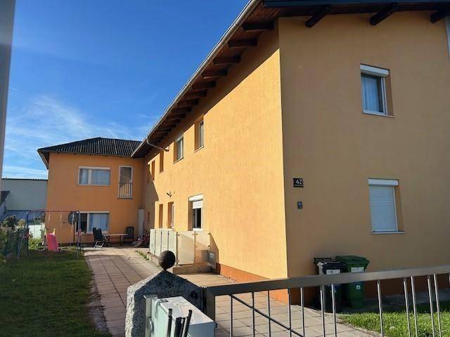 Seitenansicht des Gebäudes mit gelber Fassade, Hausnummer 43 und einem gepflasterten Zugangsbereich.