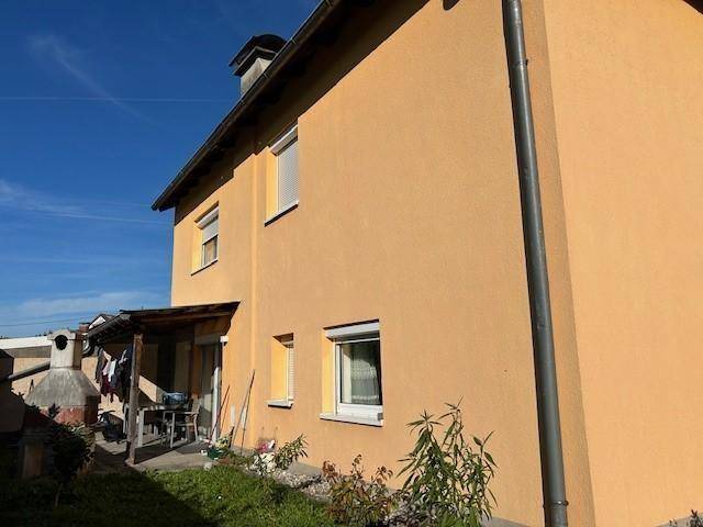 Überdachte Terrasse mit Gartenmöbeln und einem gemauerten Grillbereich an der Seite des Hauses.