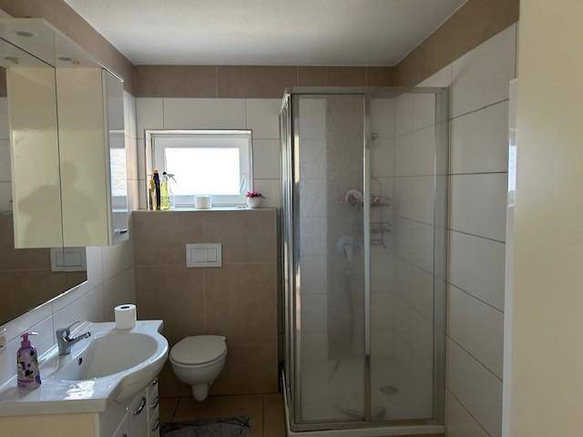 Modernes Badezimmer mit Duschkabine, wandhängendem WC, Einzelwaschbecken und einem Fenster.