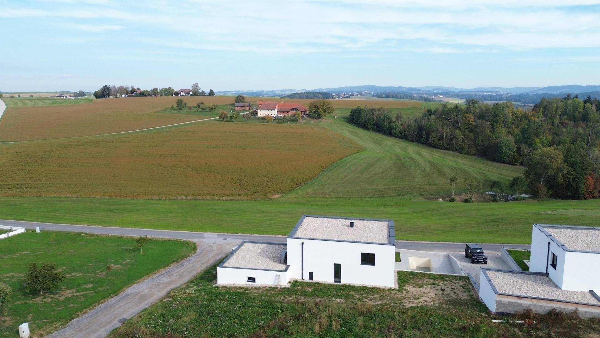 Weitläufige Landschaft mit Feldern und Wäldern, umgeben von modernen Neubauten.