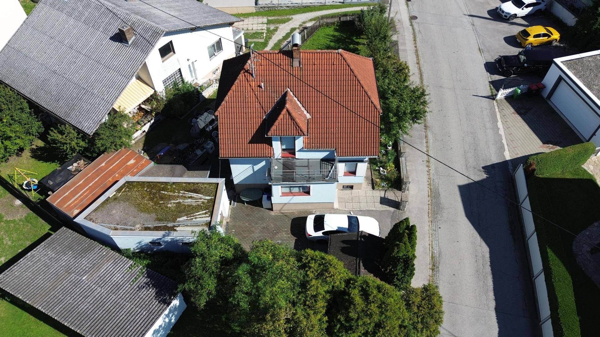 Dachaufsicht eines Einfamilienhauses mit rotem Ziegeldach, Balkon und angrenzender Garage.