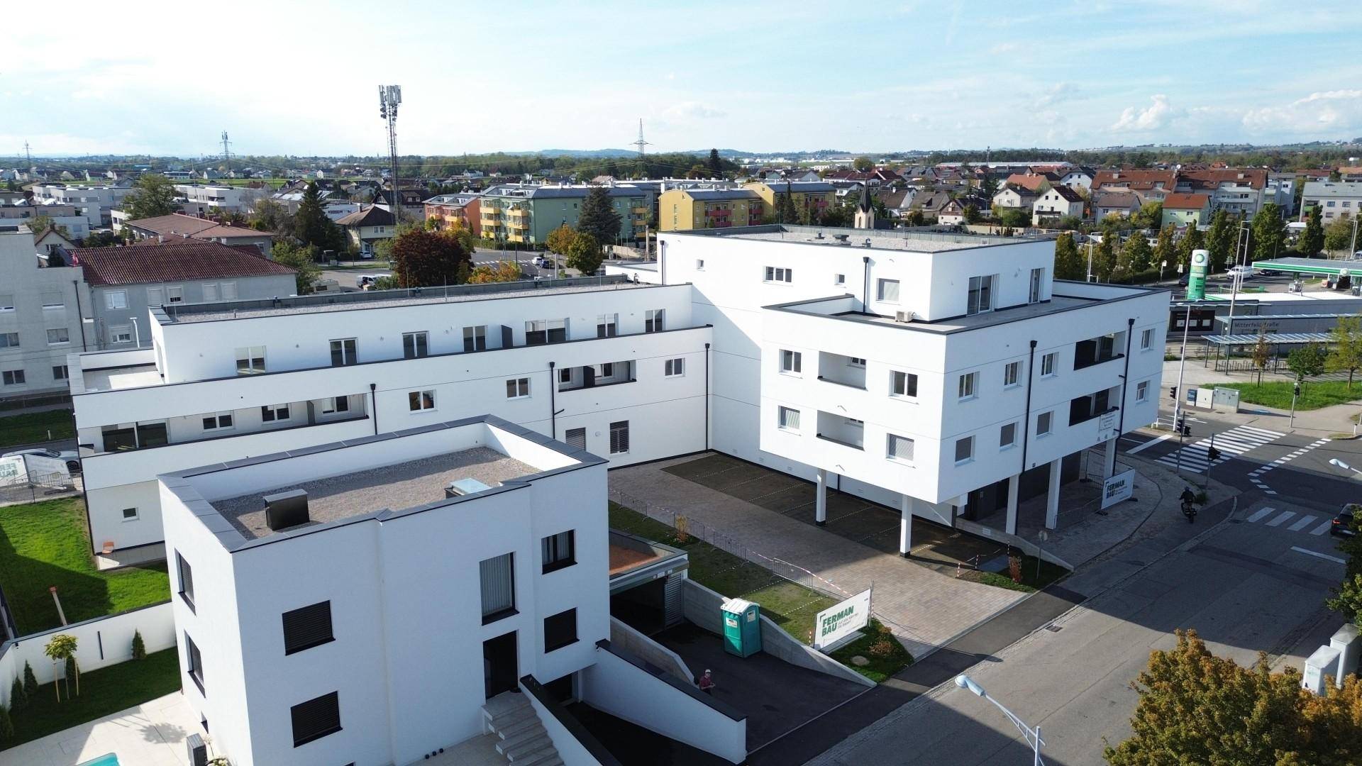 Luftaufnahme eines modernen Wohnkomplexes mit Flachdächern und umliegender städtischer Bebauung.