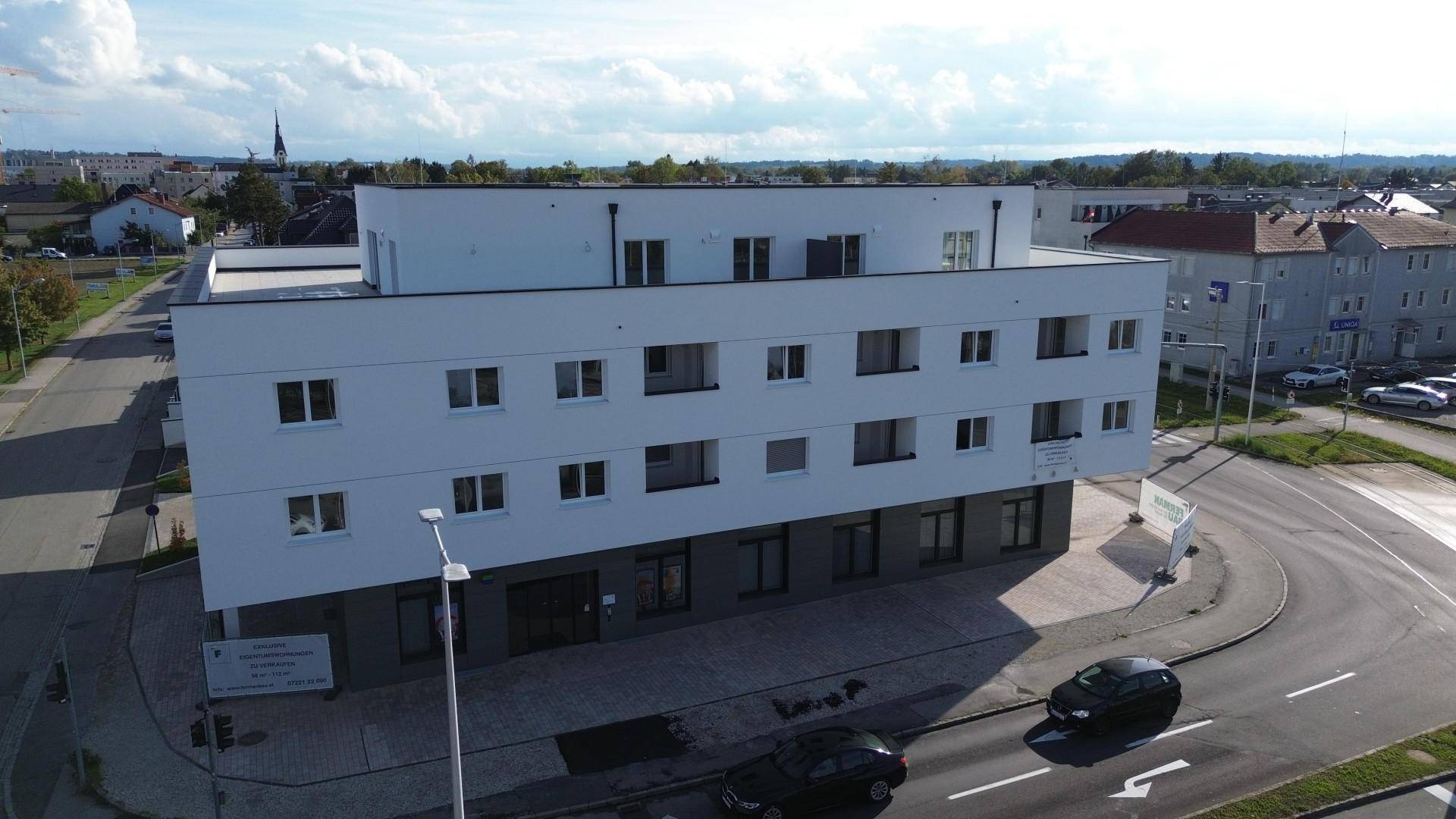 Luftaufnahme eines modernen Wohngebäudes mit Flachdächern, klaren Linien und Blick auf die Stadt.