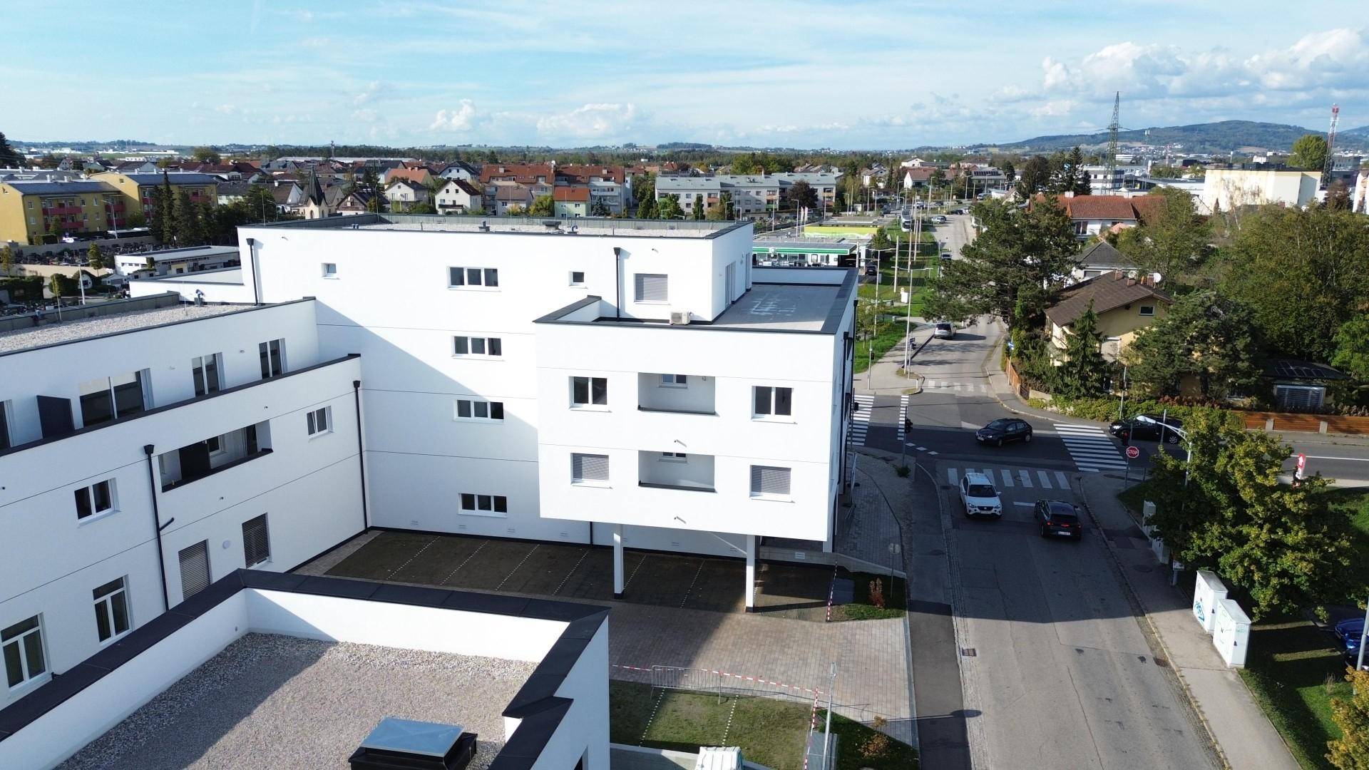 Luftaufnahme eines modernen Wohngebäudes mit Flachdächern, klaren Linien und Blick auf die umliegende Stadt.