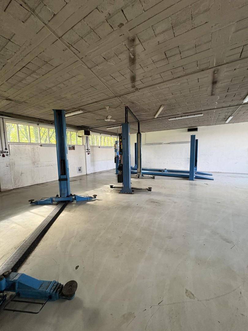 Geräumige Werkstatt mit mehreren Hebebühnen, Betonboden und Fenstern für ausreichend Tageslicht.