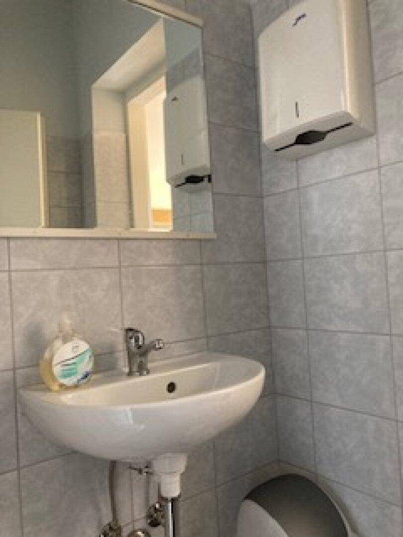 Helles Badezimmer mit Waschbecken, Spiegel und Fliesen an den Wänden, sauber und funktional.