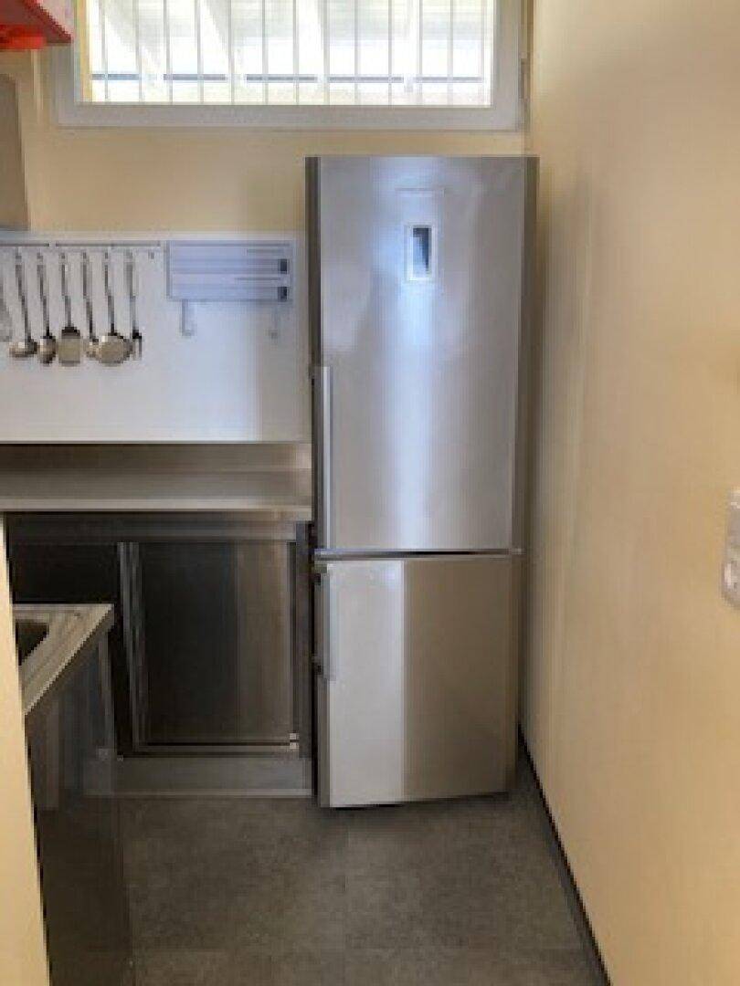 Professionelle Küche mit großem Kühlschrank und Edelstahlspüle, bereit für den Gastronomiebetrieb.
