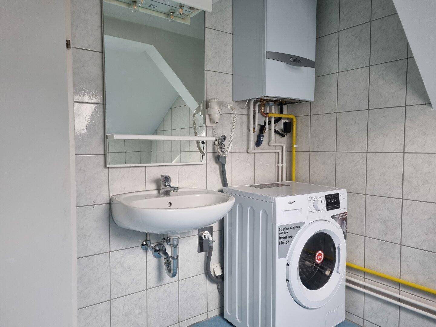 Praktischer Hauswirtschaftsraum mit Waschbecken, Waschmaschine, Gastherme und gefliesten Wänden.