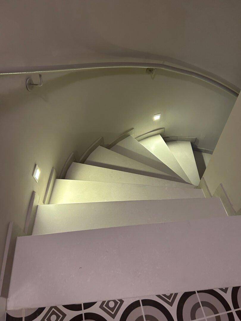 Wendeltreppe von oben gesehen mit integrierter Stufenbeleuchtung, die für Sicherheit und Ästhetik sorgt.