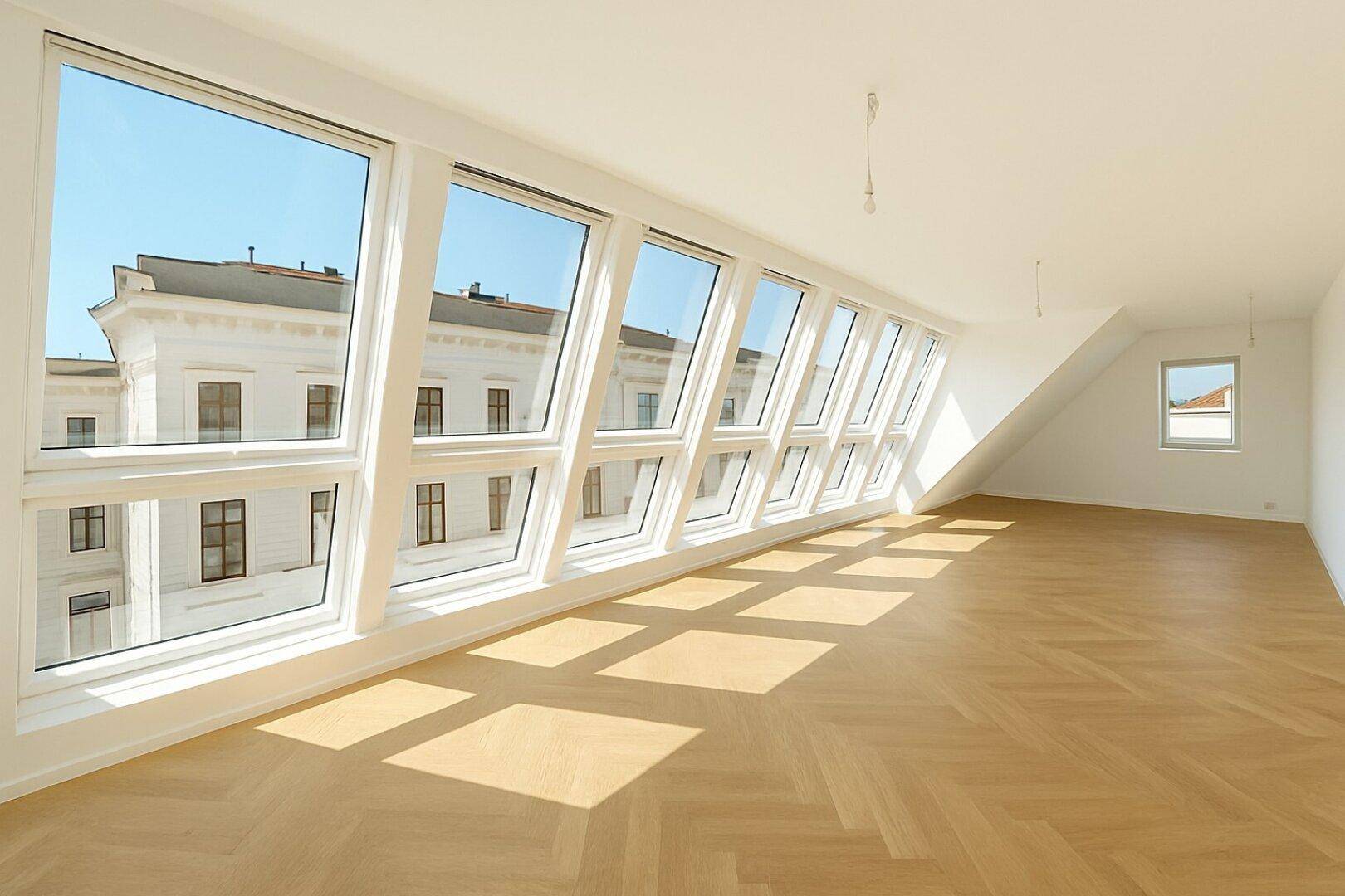 Lichtdurchfluteter Wohnbereich mit hohen Decken, Fischgrätparkett und großen Fenstern.