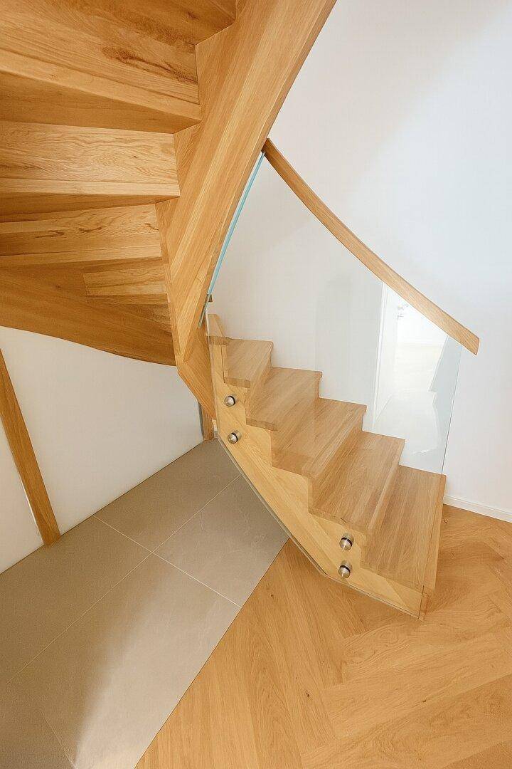 Moderne Holztreppe mit Glasgeländer, die verschiedene Ebenen des Hauses verbindet.