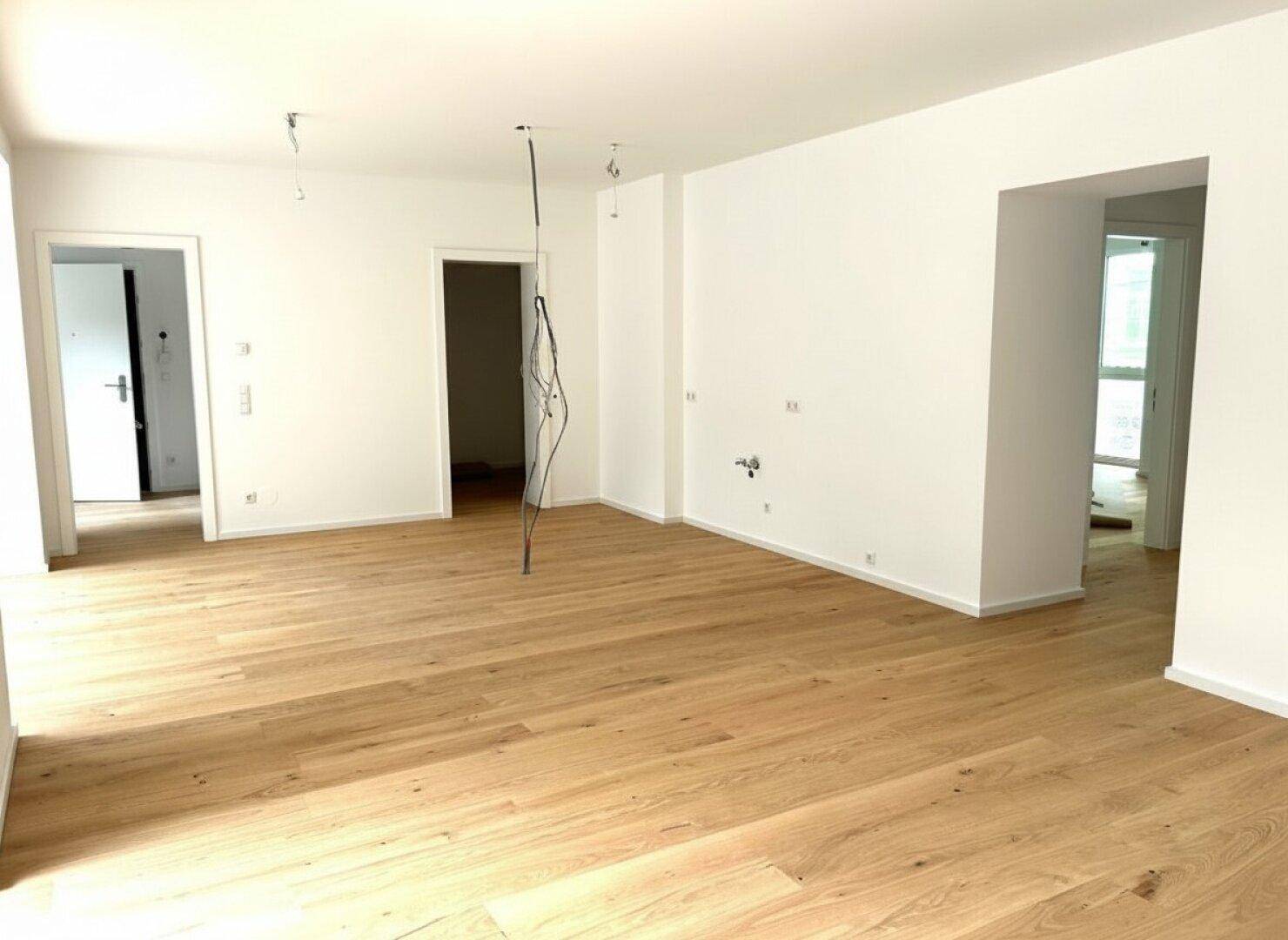 Geräumiger, unmöblierter Wohnbereich mit neuem Parkettboden und weißen Wänden, bereit zum Einzug.