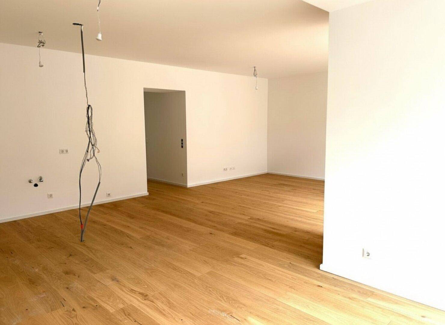 Unmöblierter Wohnraum mit neuem Parkettboden und weißen Wänden, bietet viel Gestaltungspotenzial.