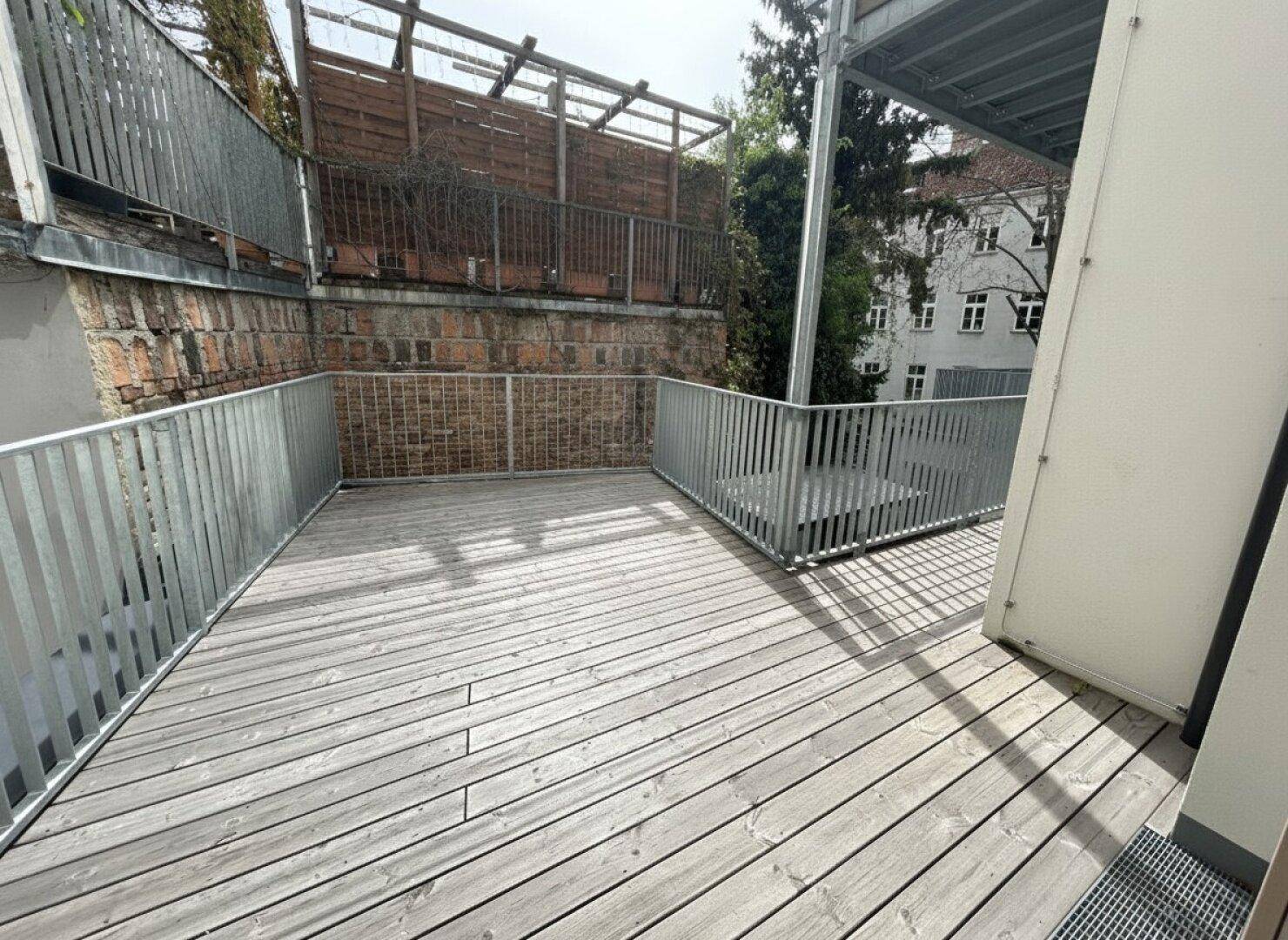 Große Holzterrasse mit modernem Metallgeländer, bietet viel Platz im Freien.