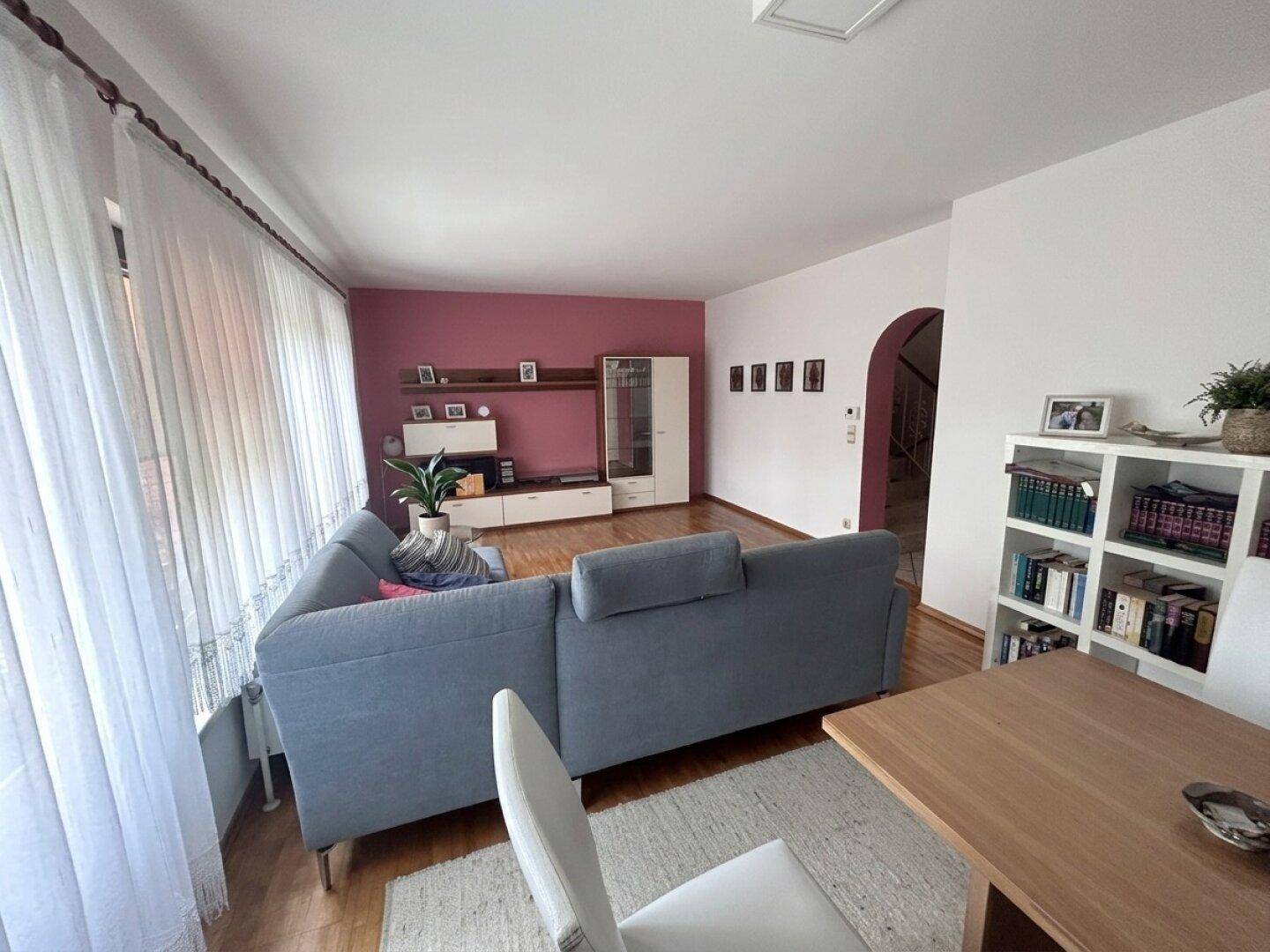 Geräumiges Wohn-Esszimmer mit Parkettboden, moderner Einrichtung und einem farbigen Akzent an der Wand.