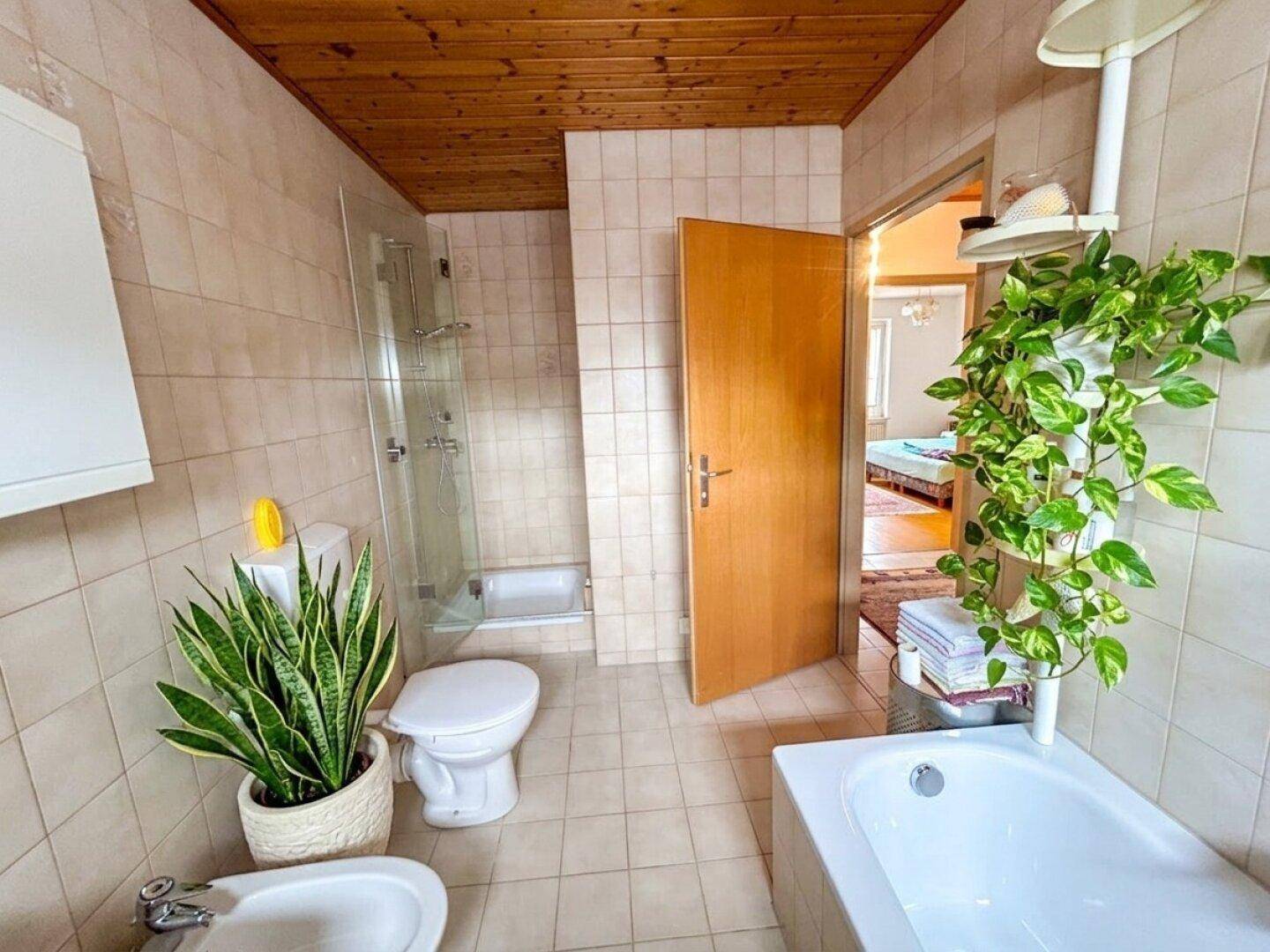Badezimmer mit Badewanne, Dusche, WC und Bidet, sowie einer Holzdecke.