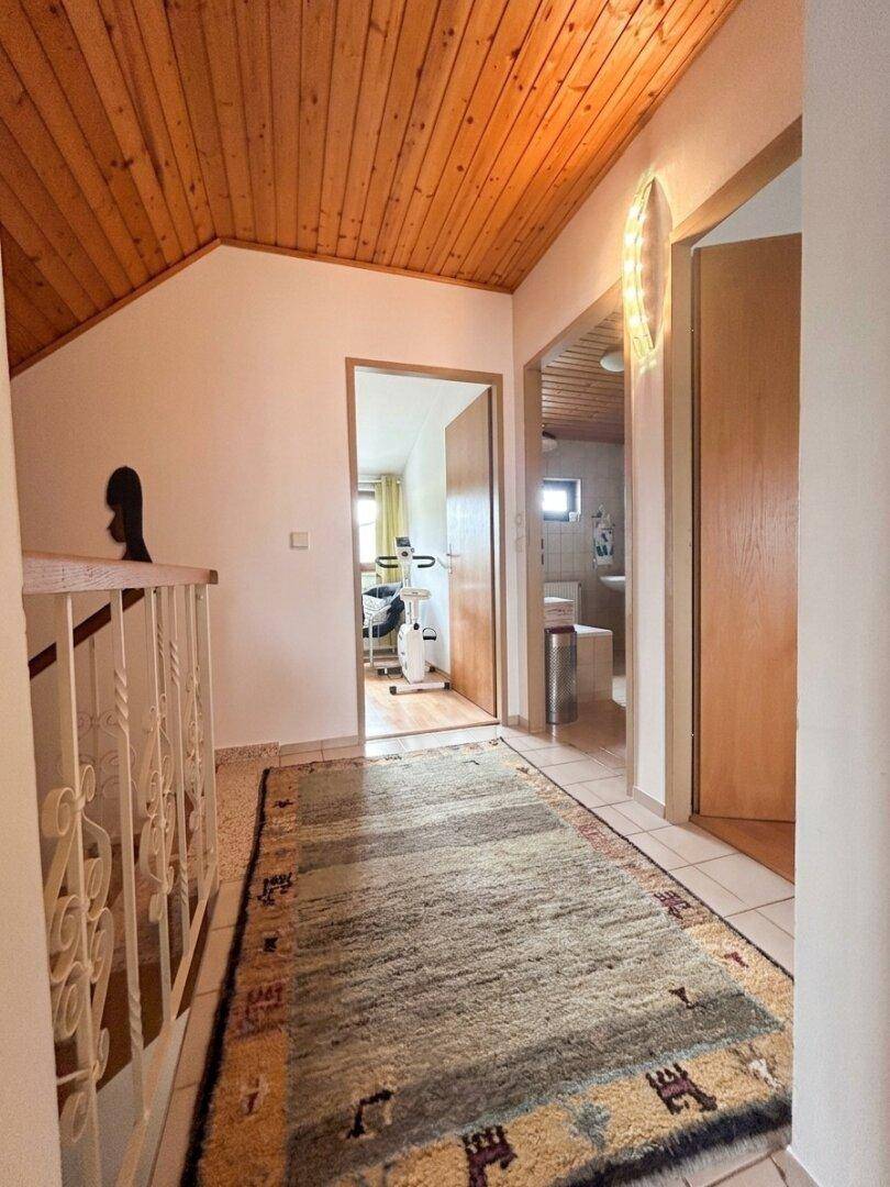 Heller Flur mit Holzdecke, Teppichläufer und Zugang zu verschiedenen Räumen im Obergeschoss.